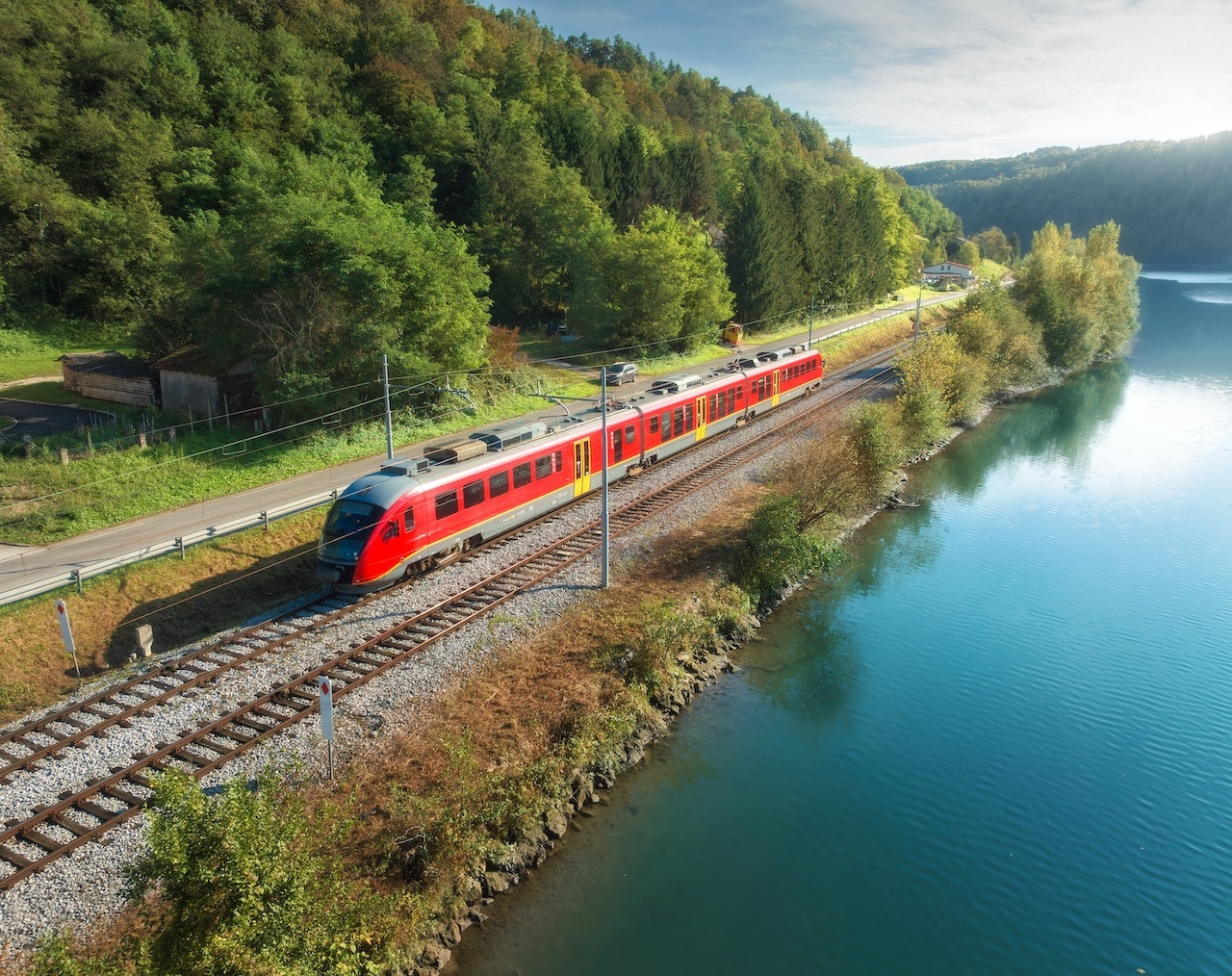 Aerial view of red modern high speed train moving near a river